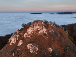 Sunset with clouds, sun rays, and misty valleys witn forest, mountain and peak nature landscape.