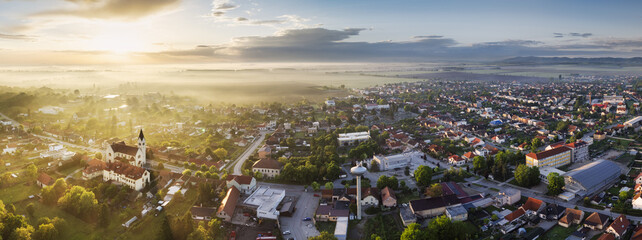 Panorama landscape with rural village at dramatic foggy sunrise. Countryside landscape