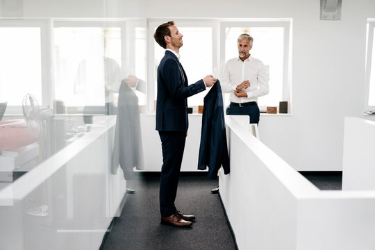 Employee in office holding jacket for his boss