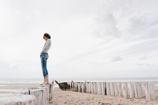 Woman standing on wooden stake on the beach