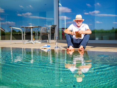 Senior man reading e-book at swimming pool