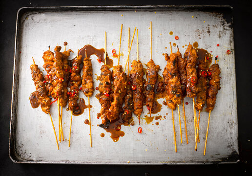 Chicken satay skewers with chili peanut sauce on baking tray