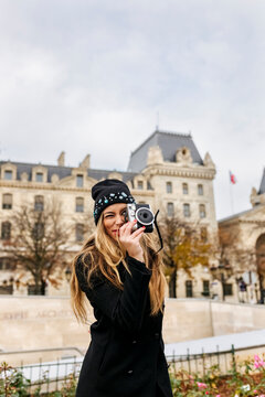 France, Paris, young woman taking picture with camera