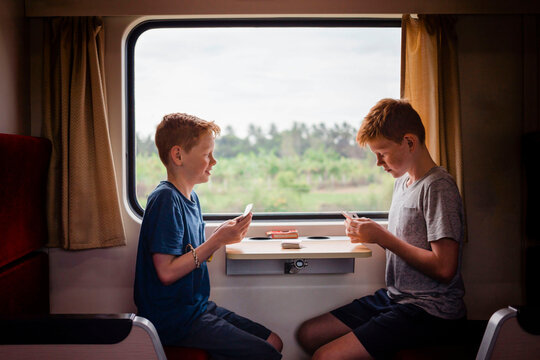 Side view of boys playing cards while traveling in train, Thailand, Asia