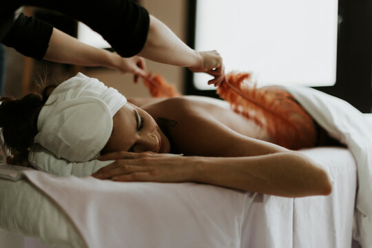 Young woman receiving a massage with feathers in a spa