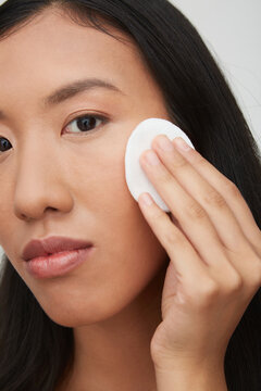 Portrait of young female Chinese woman, using cotton pad