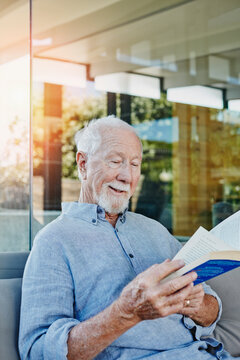 Senior man sitting on terrace reading book