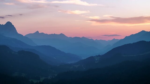 Aerial view of mountain ranges fading into the distance with a soft pink and blue sky, creating a serene and majestic landscape, Krun, Bavaria, Germany.