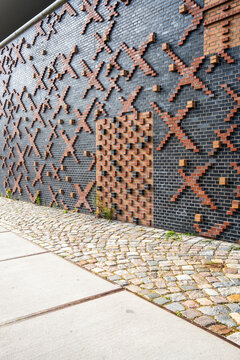 Close detail of modern urban brick wall showing architecture facade pattern and texture across pavement creating a strong graphic surface design