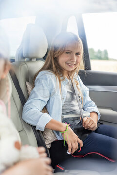 Girl sitting in car, fastening seat belt