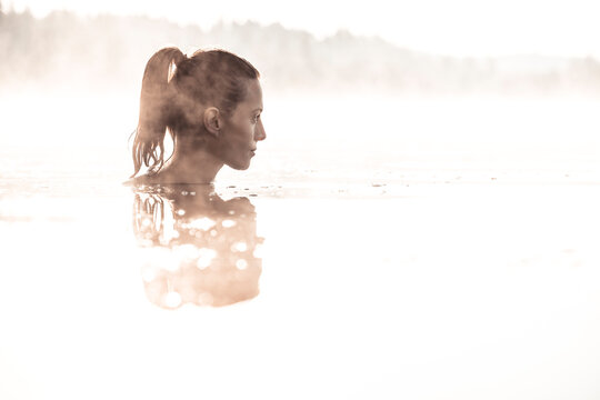 Woman bathing in a lake at morning mist