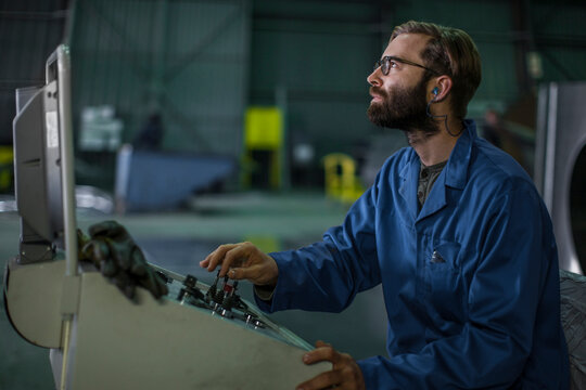 Worker operating machinery at control panel in factory