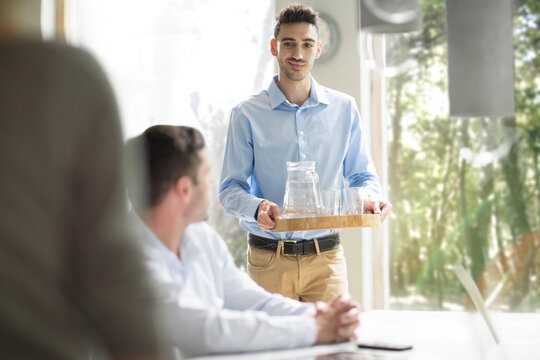 Young man serving water at a business meeting