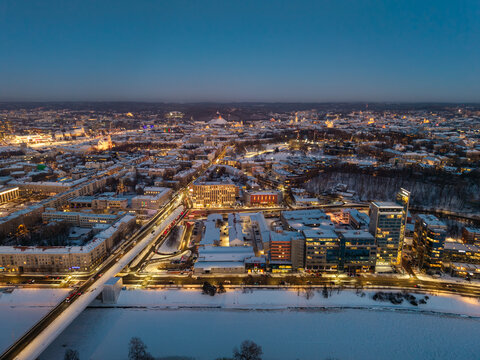 Aerial drone view of Vilnius during winter blue hour, featuring the Neris River, Liubartas Bridge, Old Town, and Tauras Hill illuminated as night falls.