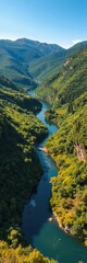 Obraz premium A winding river flowing through a lush, green valley, reflecting the surrounding vegetation, watercourse, riparian