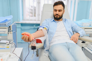 Fototapeta premium Young man donating blood in medical clinic for charity