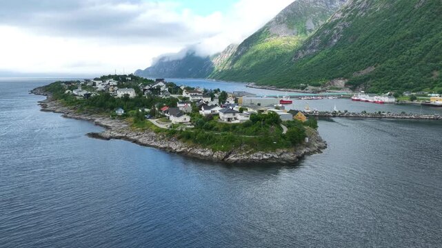 Aerial, orbit drone flight, view from fjord on Hus&oslash;y island and village Amazing wild nature in summer on Senja island in Norway. Beautiful landscape, wild nature. Fjord, mountains. Travel destination.