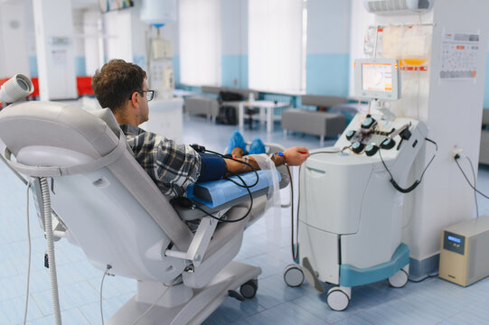 Man donating blood plasma through medical apheresis machine