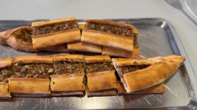 Turkish pide with minced meat filling on a metal tray, showing traditional baked bread dish