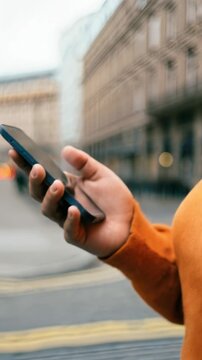 Woman using a smartphone while walking in an urban street, vertical shot