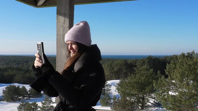 Kaliningrad landmarks. Efa Dune in winter, a popular vantage point overlooking the Baltic Sea. A woman photographs the frozen landscape from the observation deck.