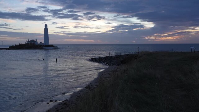 A panoramic wide shot of St Mary&rsquo;s Lighthouse on its tidal island, captured from the rugged low cliffs of Whitley Bayat dawn
