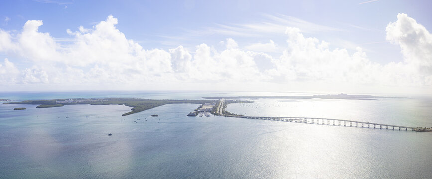 Aerial view of a bridge stretching over the vast, shimmering turquoise ocean towards the lush green island of Key Biscayne, Key Biscayne, Florida, United States.
