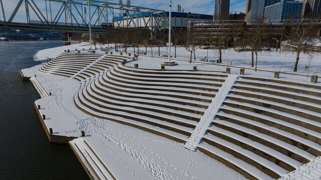 Aerial view of snow-dusted steps leading down to the river under a bridge near the stadium create a serene winter scene., Cincinnati, Ohio, United States.