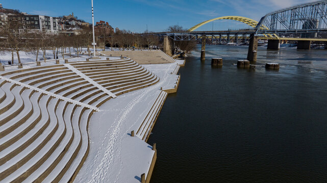 Aerial view of the snow dusted steps of the Theodore M. Berry International Friendship Park leading to the serene Ohio River, with bridges arching in the distance, Cincinnati, Ohio, United States.