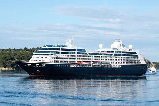 View of a large cruise ship glides through the shimmering Adriatic waters, its sleek lines cutting a path toward the ancient shores, Sibenik, Croatia.