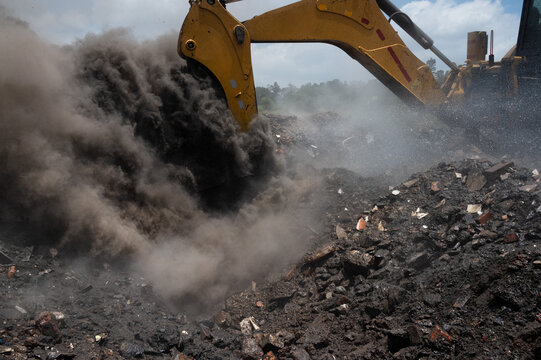 A cloud of smoke and steam explodes as excavator assisting firefighters to extinguish an underground fire on an illegal waste dump in Kyasands, South Africa.