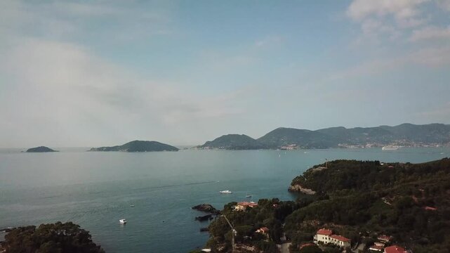 Fly Over and panoramic coastal view over the Gulf of La Spezia, Gulf of Poets, Liguria, Italy, calm sea, distant headlands islands and hills, with Mediterranean vegetation in foreground.