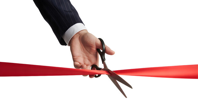 Businessman cutting red ribbon with scissors for grand opening ceremony
