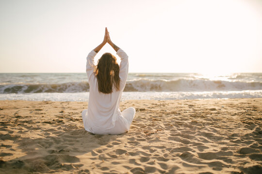 Beautiful 40 years old woman having yoga exercises on th beach at sunset.