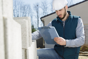 Fototapeta premium workman with clipboard checking delivery of concrete blocks