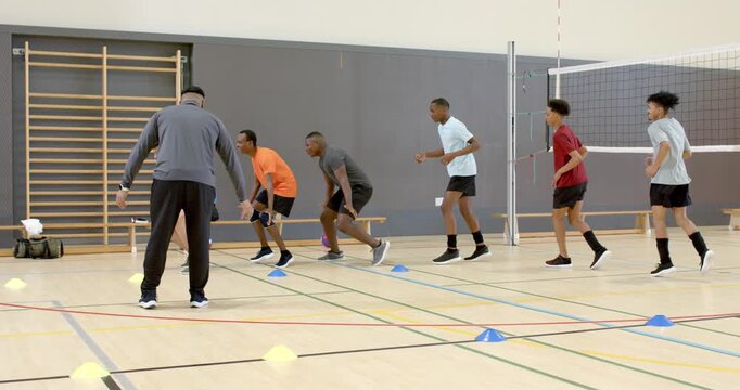 Coach giving cue, players reacting with lateral sprints between cones in gym for footwork training