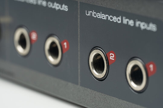 Macro close-up of professional audio interface rear panel featuring 1/4 inch line inputs and outputs, TRS jack connectors for studio recording and music production equipment.
