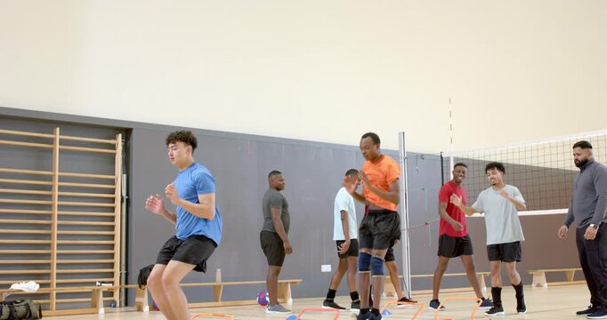Coach calling instructions, volleyball teammates running through obstacles, jumping to block in gym
