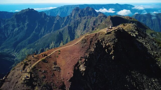 4K Drone Orbit of Pico Ruivo Summit, Highest Point of Madeira: Dramatic North Slope Shadows, Hikers on PR1.2 Vereda Trail, Volcanic Ridge Above Clouds, Atlantic Ocean Background, Cinematic Shot
