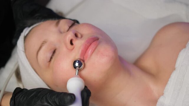 Caucasian woman receiving electric microcurrent facial treatment. Cosmetologist performing a relaxing procedure for skin rejuvenation