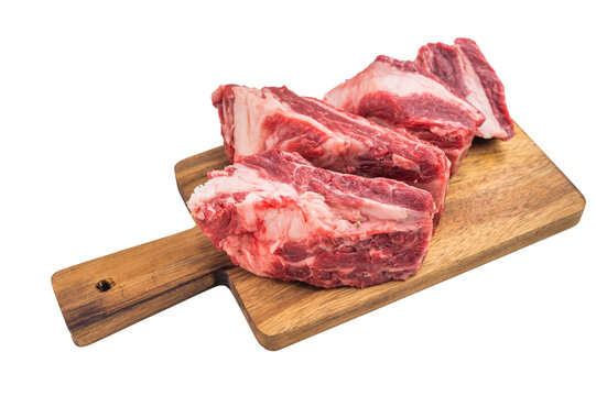 Raw beef short ribs cut into pieces on wooden board isolated on white background. Fresh meat portions for braising soup broth and BBQ..