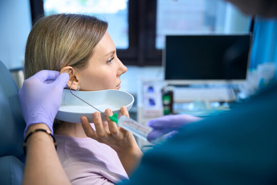 Otolaryngologist doctor removing earwax with water and a syringe for female patient