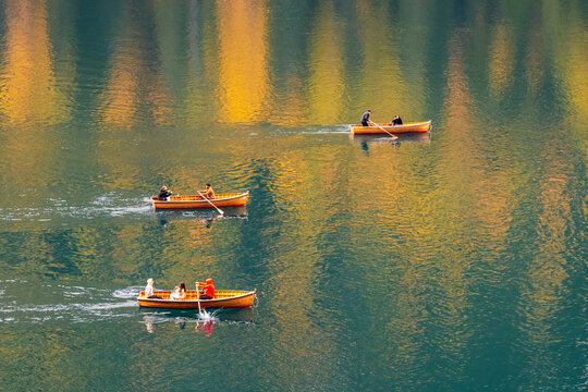Three wooden rowboats on a calm lake reflecting autumn colors. Braies lake,Alto Adige,Dolomites,Italy