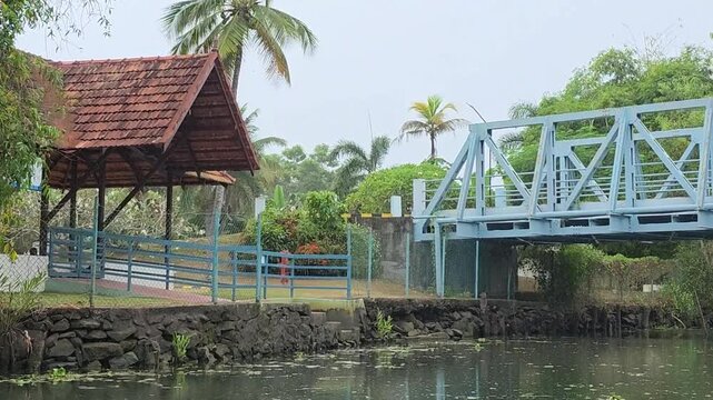 Blue pedestrian bridge over calm water in Kerala