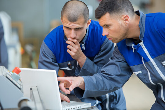 handsome auto mechanic and apprentice with laptop