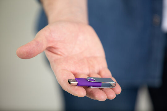 mans hand holding flash drive