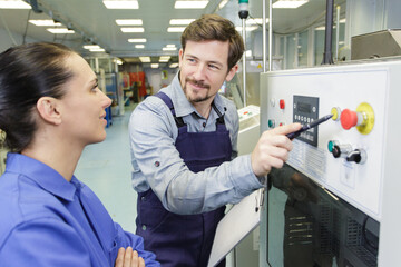 Obraz premium man and woman operating a machine in a factory