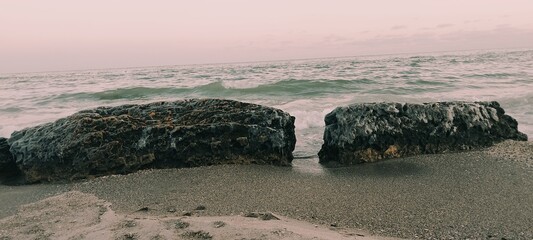 Frozen sea boulders and icy rocks on a sandy beach at sunset. Dramatic winter coast with ocean waves, salt crystals, and arctic textures. High-quality nature photography for commercial use. © Natul'ka