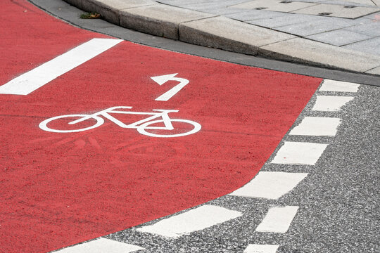 Curving bicycle bike lane with red asphalt road marking in Hamburg showing urban lane design direction and regulated traffic movement