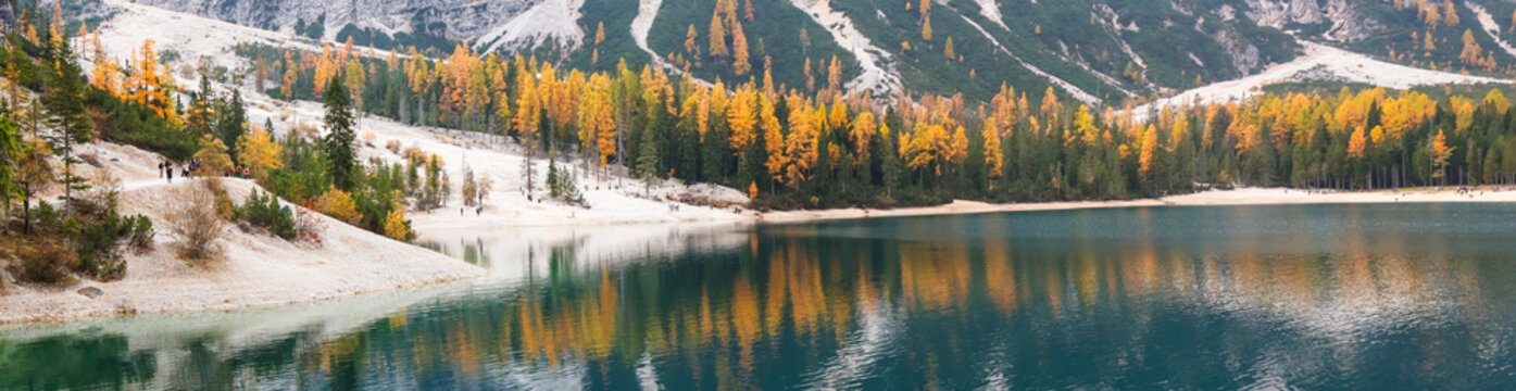 Scenic view of a calm, turquoise lake reflecting autumn trees and mountains. Braies lake,Alto Adige,Dolomites,Italy